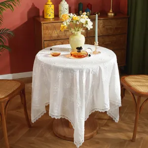 Elegant white round tablecloth with floral embroidery and delicate lace edges in a cozy home setting
