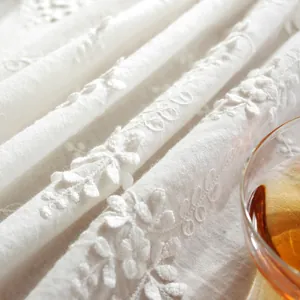Close-up of white table cloth with detailed 3D floral embroidery and lace texture