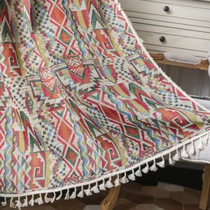 Bohemian geometric woven throw blanket with white fringe on a vintage wooden chair