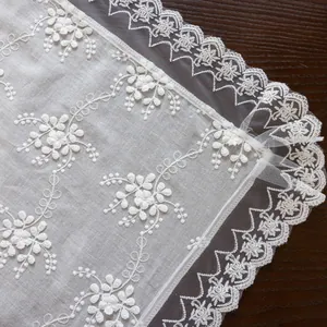 Close-up of white 3D floral embroidery on lace tablecloth with delicate wavy edges
