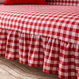 Close-up of red gingham cotton sofa cover fabric featuring elegant ruffle hem detail