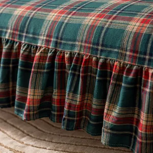 Detail of red and green plaid sofa cover featuring elegant ruffle edges and soft texture
