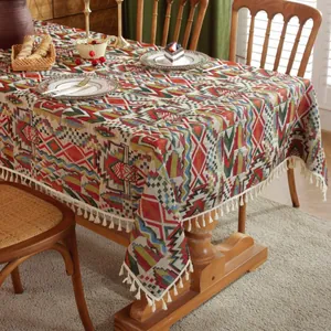 Boheems geometrisch tafelkleed met witte kwastjes op houten eettafel in sfeervol decor