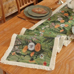 Detail of floral jacquard table runner with fringe on a rustic wooden dining table