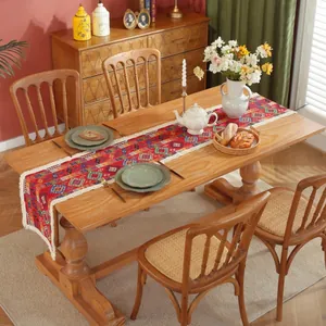 Runner da tavola etnico con motivi geometrici rossi e nappe bianche su tavolo in legno