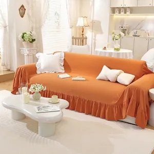 Detail of orange ruffle hem sofa cover with elastic knit texture and decorative flounce