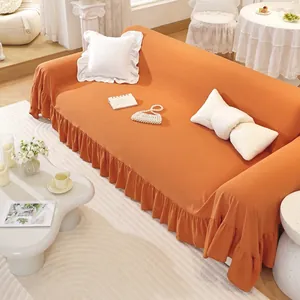 Detail of orange ruffle hem sofa cover with elastic textured fabric and elegant pleats