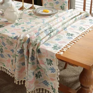 Gros plan de la nappe à imprimé feuilles avec des pompons décoratifs de couleur crème