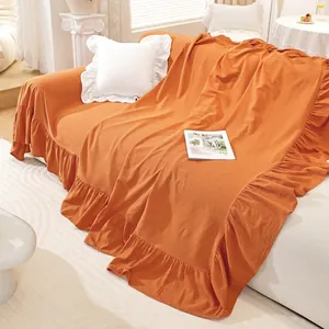 Detail of warm terracotta sofa cover with elegant ruffle edges and linen texture