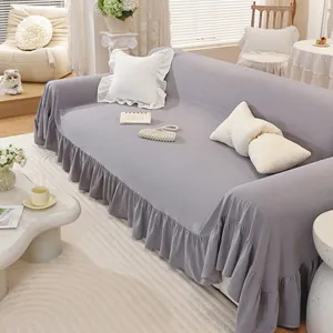 Close-up of elegant ruffled skirt hem on a solid gray cotton sofa cover in cream style room