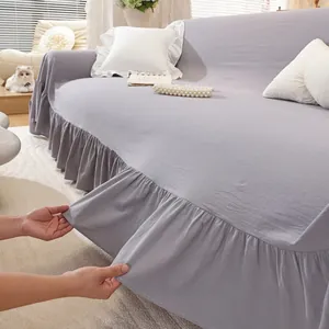 Detail of ruffle edge sofa cover in linen texture featuring soft purple-grey fabric draping