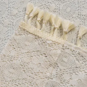 Macro shot of beige hollow lace curtain with crochet geometric patterns and tassels