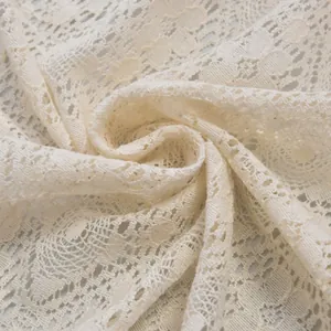 Detailed close-up of beige hollow lace fabric with floral crochet patterns and soft texture
