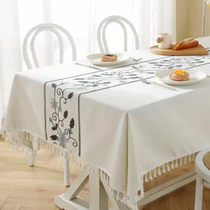 Close-up of beige Christmas tablecloth with blue floral embroidery and white fringe edges