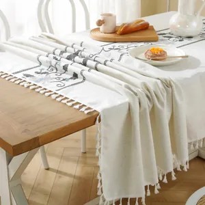 Macro view of cream floral embroidery on linen table runner with white tassels decor