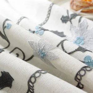 Detail of white cotton linen tablecloth featuring floral embroidery and soft fabric texture