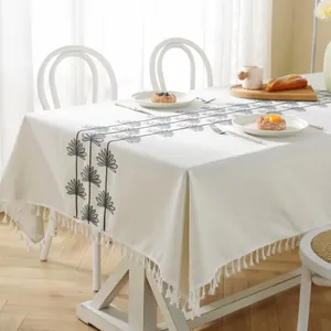 Detail of beige Christmas tablecloth with black floral embroidery and white fringe tassels