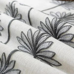 Close-up of beige linen tablecloth with dense grey petal embroidery and thick texture
