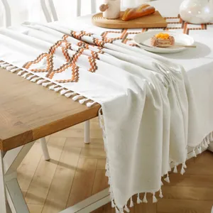 Detail of beige Christmas tablecloth with orange geometric pattern and fringe tassels