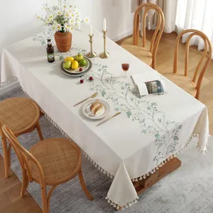 Pastoral cream table cloth with green leaf embroidery and ball fringe tassels on a table