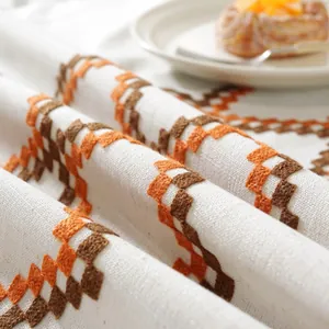 Detailed view of jacquard table cloth with orange geometric embroidery on cotton linen fabric