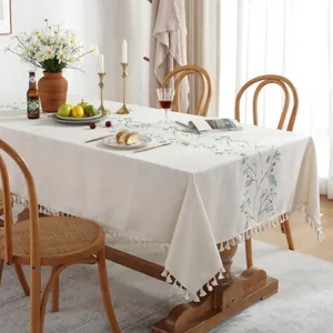 Floral embroidered cotton linen tablecloth with tassel trim in a cozy rustic dining room