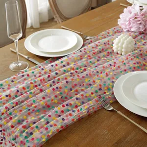 Tafelloper van gaas met gekleurde stippen op een houten tafel met feestdecoraties