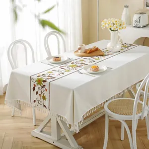 Detail of beige Christmas tablecloth featuring floral embroidery and delicate fringe edges