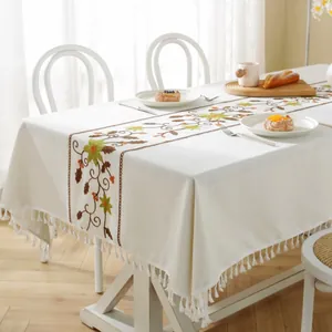 Close-up of white jacquard tablecloth with floral embroidery and tassel fringe edges