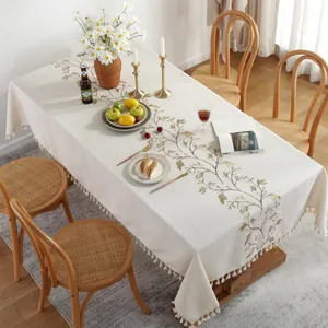 Detail of French floral embroidery and cream fringe tassels on linen tablecloth