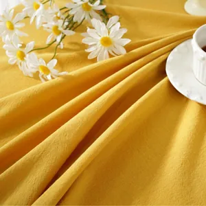 Detailed texture of ginger yellow linen tablecloth with elegant lace trim and soft folds