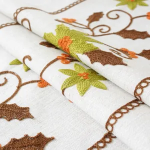 Close-up of luxury festive tablecloth featuring botanical embroidery and lace edges