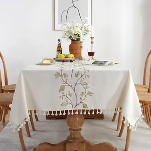 Detailed embroidery of leaves on linen tablecloth with elegant white fringe tassel edges