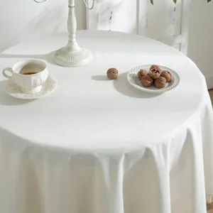 Minimalistisch gebroken wit rond tafelkleed met kwastjes op een houten tafel