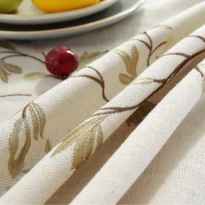 Detailed close-up of beige jacquard tablecloth with gold leaf embroidery and tassels