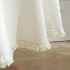 Detail van crème katoen linnen tafelkleed met fijne franjes en geweven textuur