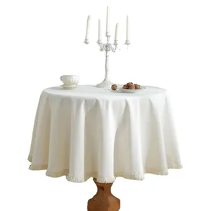 Minimalistisch beige rond tafelkleed met kwastjesrand op witte achtergrond