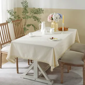 Rectangle off-white linen tablecloth with fringe tassels on a dining table setup