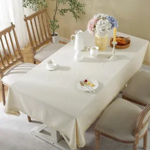 Rectangular cream linen tablecloth with tassel edges in a minimalist cozy dining room