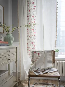 Detail of floral embroidery and beige tassel fringe on linen blend window curtains