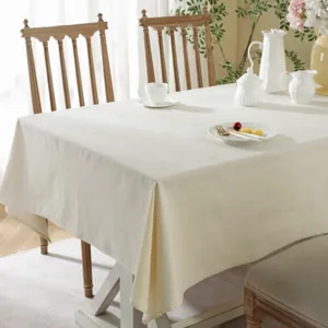 Elegant cream linen rectangular tablecloth on a wooden table with ceramic decor