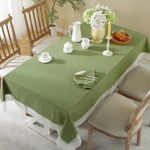 Detail van het grasgroene katoenen linnen tafelkleed met witte kant aan een eettafel