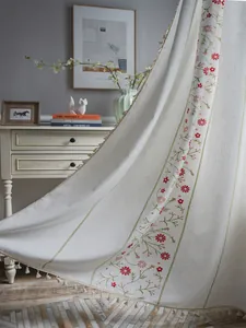 Close-up of floral embroidery and tassel fringe on beige semi-blackout cotton curtains