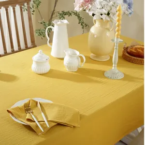 Detailed close-up of textured mustard cotton tablecloth with fine stitching and napkin