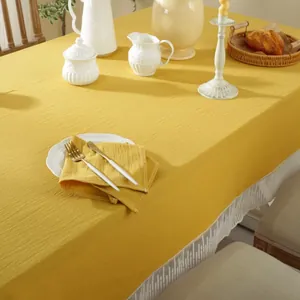 Detail van geel katoenen linnen tafelkleed met witte kanten rand en zachte textuur