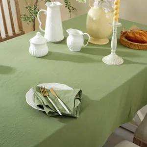 Detail of moss green cotton tablecloth with natural crinkle texture and matching napkins