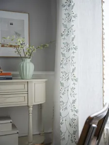 Detail of linen-textured green floral embroidery curtain with cream tassel edge fringe