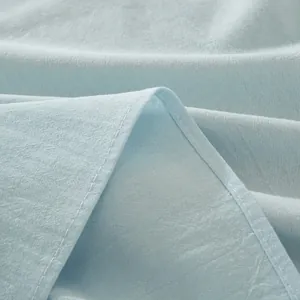Detailed close-up of light blue cotton fabric texture with clean double stitching edges