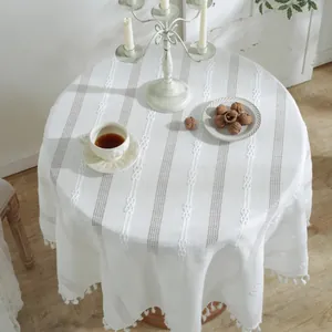 Macro detail of white jacquard tablecloth texture with elegant tassel edges on a table