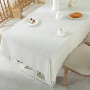 Minimalist white tablecloth with braided jacquard pattern and handmade tassels on rectangular table
